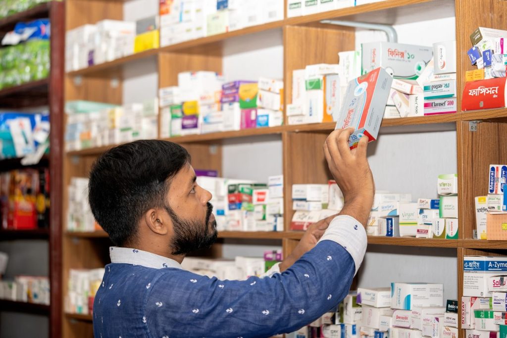 Apotheker bij rekken met geneesmiddelen